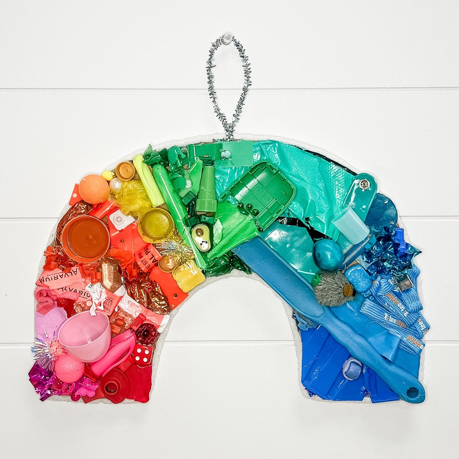 Colorful plastic bag sculpture shaped like a rainbow on a white wooden background