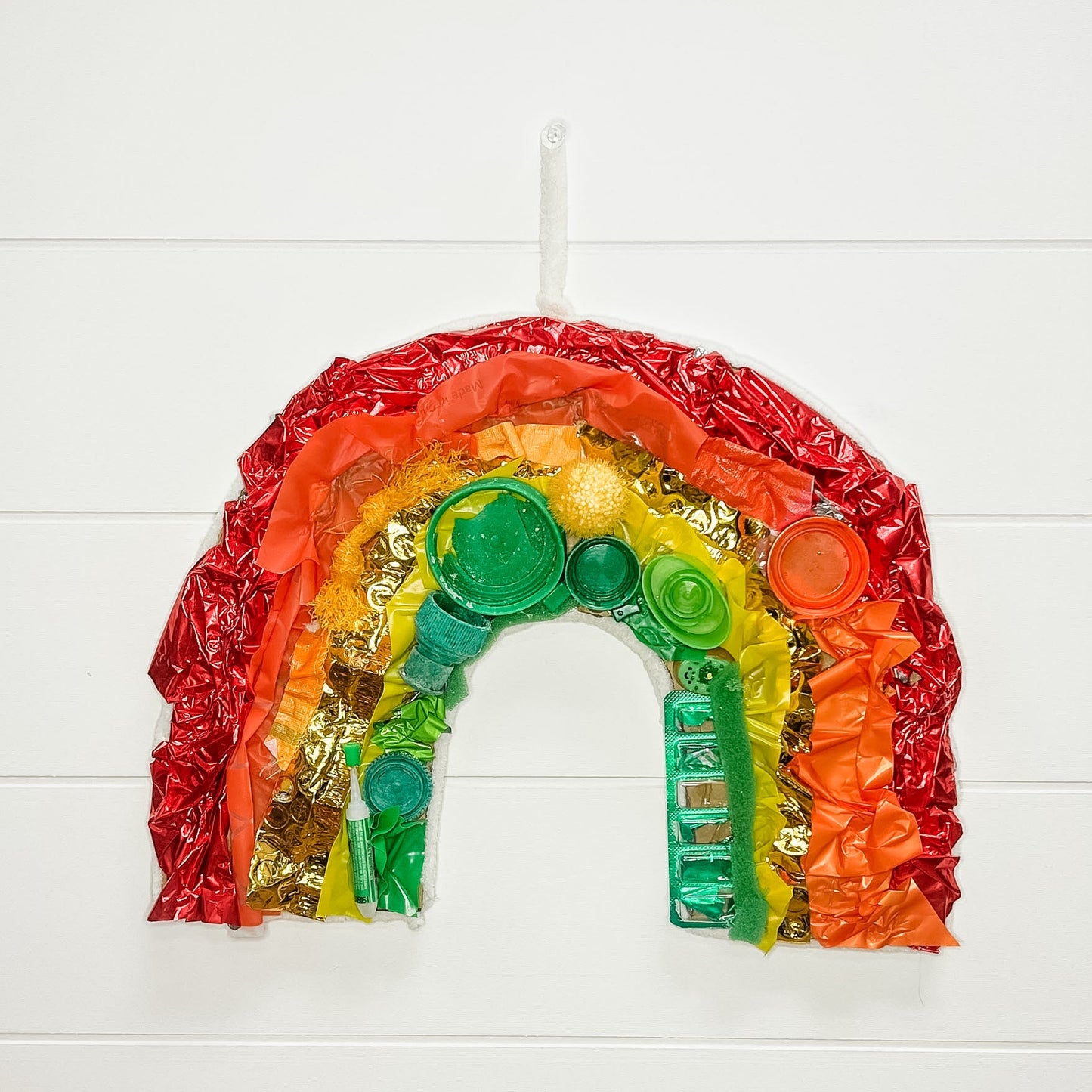 Colorful rainbow-shaped craft made from recycled materials on a white background