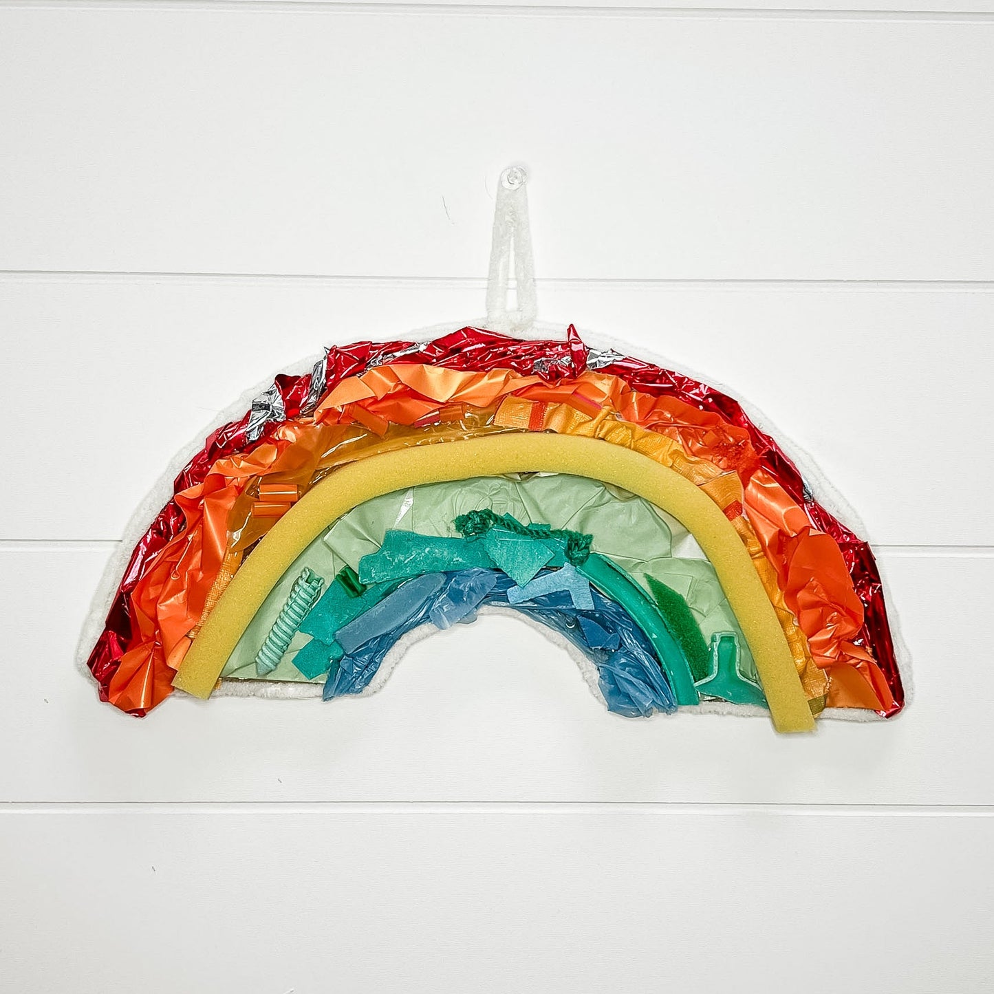 Colorful rainbow-shaped object on a white wooden background