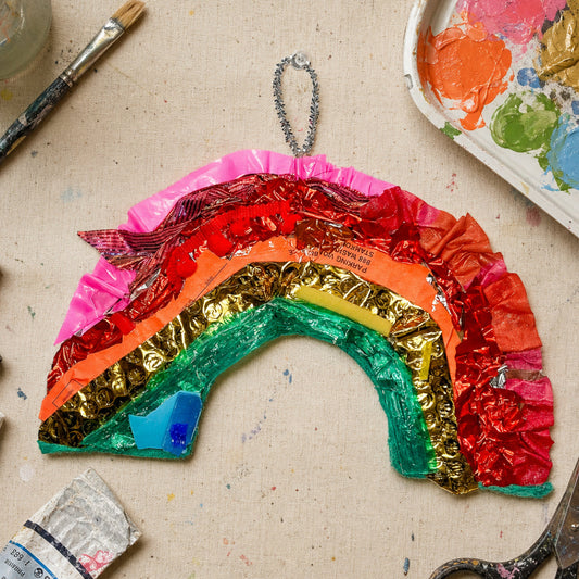 Colorful paper rainbow craft on a table with art supplies