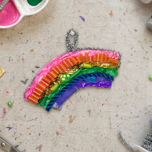 Colorful rainbow craft on a textured surface with art supplies.